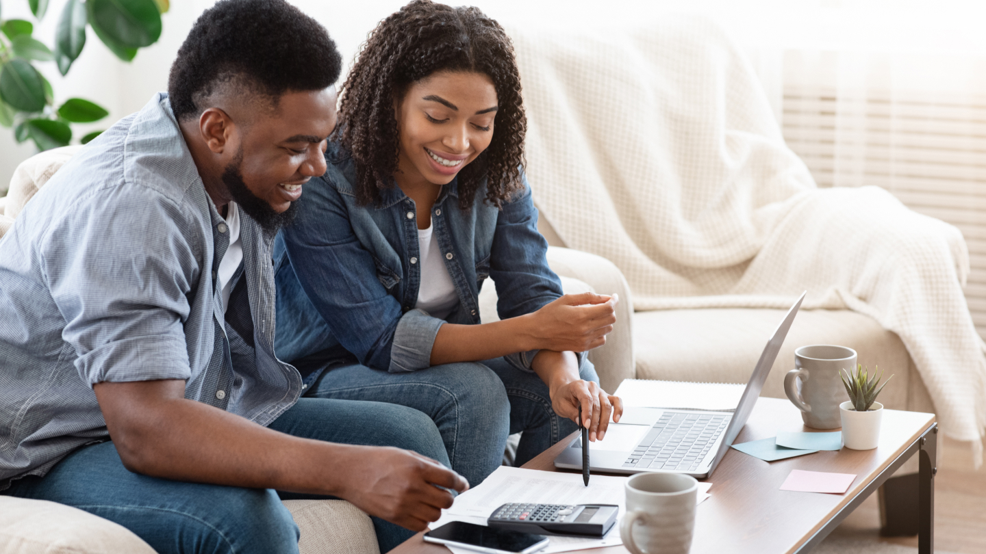 Một cặp vợ chồng đang ngồi trong phòng khách của họ và kiểm tra hóa đơn năng lượng của họ trực tuyến.
